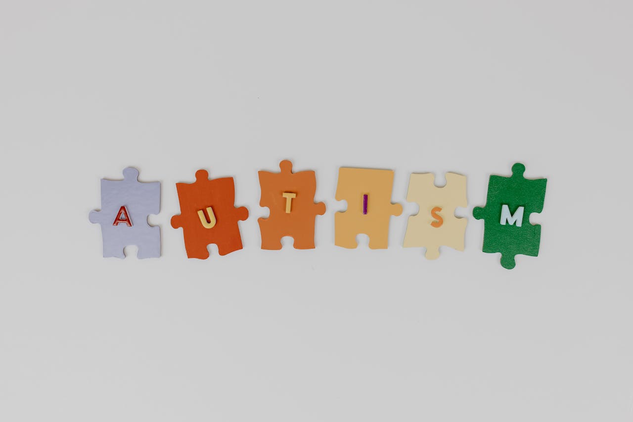 Colorful puzzle pieces spelling autism on a white background, promoting awareness.