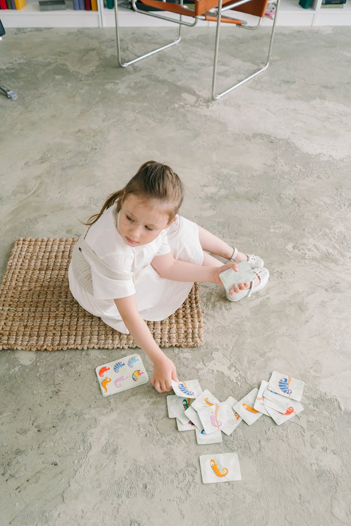Young girl engaging in developmental learning using visual cards on a woven mat.